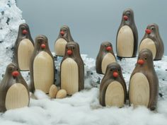 a group of wooden penguins standing next to each other on snow covered ground with trees in the background