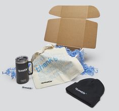 an open cardboard box, coffee mug, and other items to be packed into it