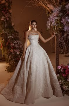 a woman standing in front of a mirror wearing a wedding dress with flowers on it