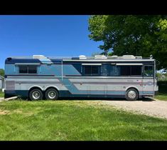 an rv parked on the side of a dirt road in front of a green field