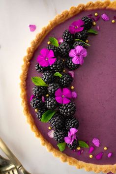 a purple dessert topped with blackberries and flowers