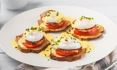 three pieces of toast with eggs and tomatoes on them next to a cup of coffee