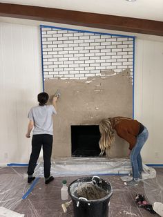 two women are painting a brick fireplace in a room with white paint on the walls