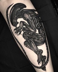 a black and white tattoo with an alien on it's arm, holding a chain