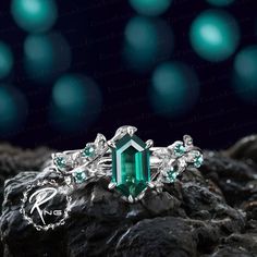 an emerald colored ring sitting on top of rocks