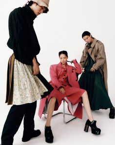 three women in coats and dresses sitting on chairs