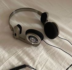 a pair of headphones sitting on top of a white sheet covered bed next to an mp3 player