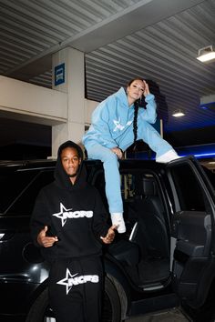 a woman sitting on top of a man's head in front of a car