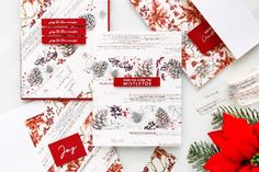 some red and white christmas cards on top of each other next to a poinsetti