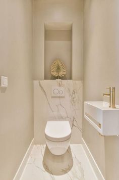 a white toilet sitting inside of a bathroom next to a wall mounted faucet