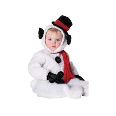 a little boy dressed in a snowman costume sitting on the ground wearing a hat and scarf