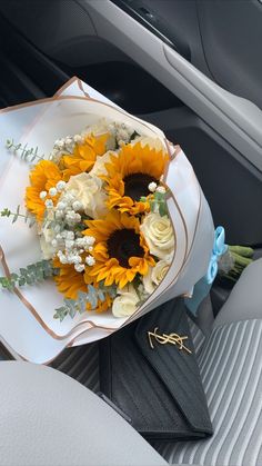 a bouquet of sunflowers sits on a plate in the back seat of a car