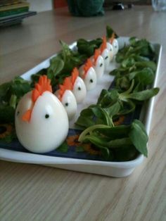 eggs with carrot heads are arranged in a row on a blue and white platter