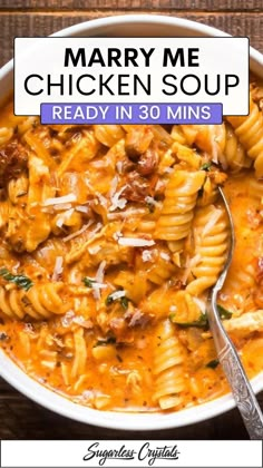 a white bowl filled with chicken and pasta soup on top of a wooden table next to a spoon