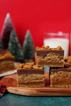 several pieces of cake sitting on top of a wooden cutting board next to a glass of milk