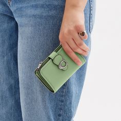 Crafted of smooth leather this bi-fold Tabby medium wallet is a modern take on an archival 1970s Coach design. Featuring a convenient exterior zip pocket for coins receipts earbuds and other small essentials it unsnaps to reveal ten card slots slip pockets and a full-length bill compartment. | Coach Tabby Medium Wallet - Women's - Silver/pale Pistachio Green Bifold Coin Purse With Zipper Closure, Bifold Coin Purse With Snap Closure, Compact Green Wallet With Card Slots, Green Bifold Wallet For Formal Occasions, Green Wallet With Card Slots For Formal Occasions, Formal Green Wallet With Card Slots, Coach Tabby, Large Wallet, Coach Wallet