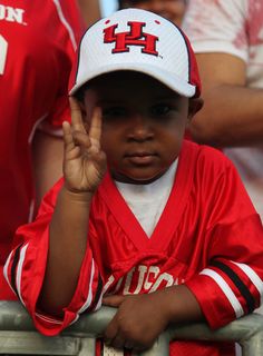 a young boy wearing a red and white baseball uniform holding his hand up in the air