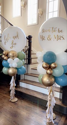 balloons and streamers are on the stairs in front of a staircase with gold, white and blue balloons