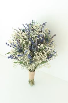 a bouquet of blue and white flowers sitting on top of a table next to a wall