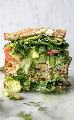 a sandwich with lettuce, tomato and cucumber on it is cut in half