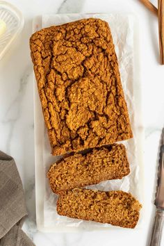 sliced oatmeal bread sitting on top of a white plate next to a knife and fork