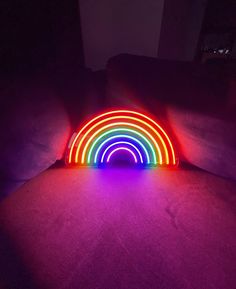 a rainbow light sitting on top of a couch in a dark room next to pillows