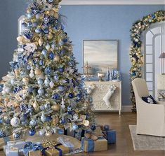 a blue and gold christmas tree in a living room with presents on the floor next to it