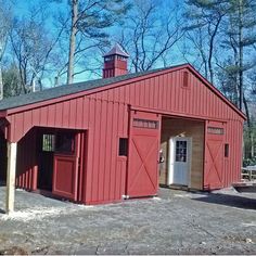 a red barn sitting in the middle of a forest