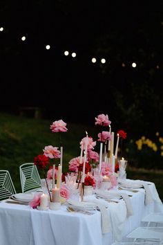 the table is set with candles, flowers and plates for an elegant dinner party in the evening