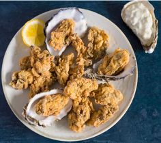 oysters on a white plate with lemon wedges