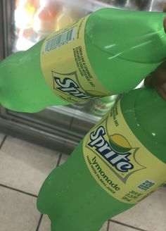 two bottles of soda sitting on top of a tiled floor