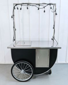 an ice cream cart with wheels and lights on the top is parked in front of a white wall