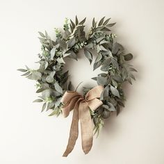 a wreath that is hanging on the wall with lights around it and some greenery