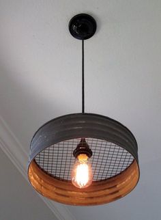 the light fixture is made out of an old barrel and has a wire basket hanging from it