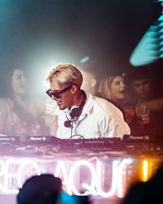 a man with headphones on standing in front of a dj