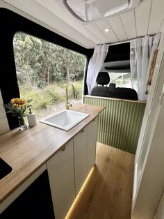 the interior of a camper with wood countertops and white cabinets, along with a sink