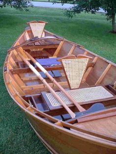 a wooden boat sitting on top of a lush green field next to a tree and grass covered ground