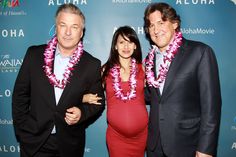 two men and a woman standing next to each other on a red carpet at an aloha event