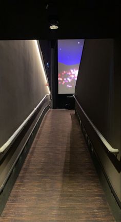 an escalator leading up to a screen on the wall