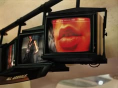 two televisions are hanging on the wall with pictures of women's mouths and lips