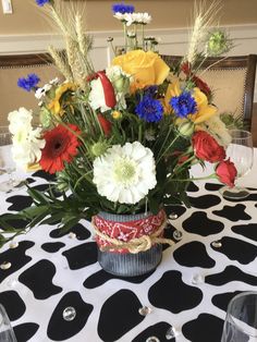 a vase filled with flowers sitting on top of a table covered in black and white polka dots