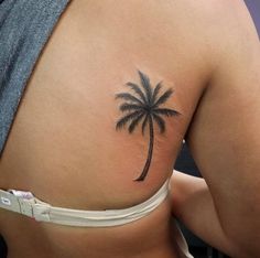 the back of a woman's stomach with a palm tree tattoo on it