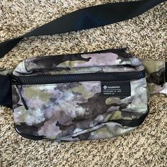 a camouflage fanny bag on the ground with an empty tag hanging from it's side