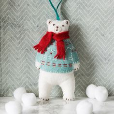 a white bear wearing a blue sweater and red scarf standing in front of snowballs