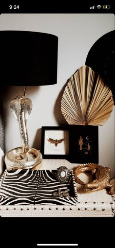 a table topped with two lamps next to a zebra print rug and framed pictures on the wall