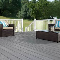 an outdoor deck with wicker furniture and blue striped pillows on the chair, coffee table and end tables