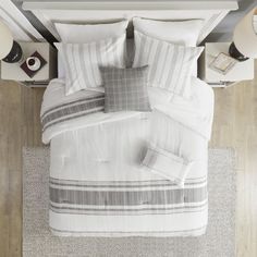 an overhead view of a bed with white and grey sheets