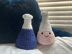 two crocheted vases sitting on top of a bed next to each other