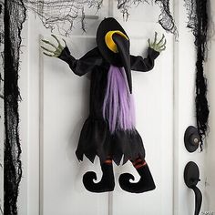 a door decorated for halloween with a black and purple witch costume hanging on the front door