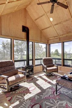 a living room filled with furniture and windows covered in wooden paneling on top of a hard wood floor